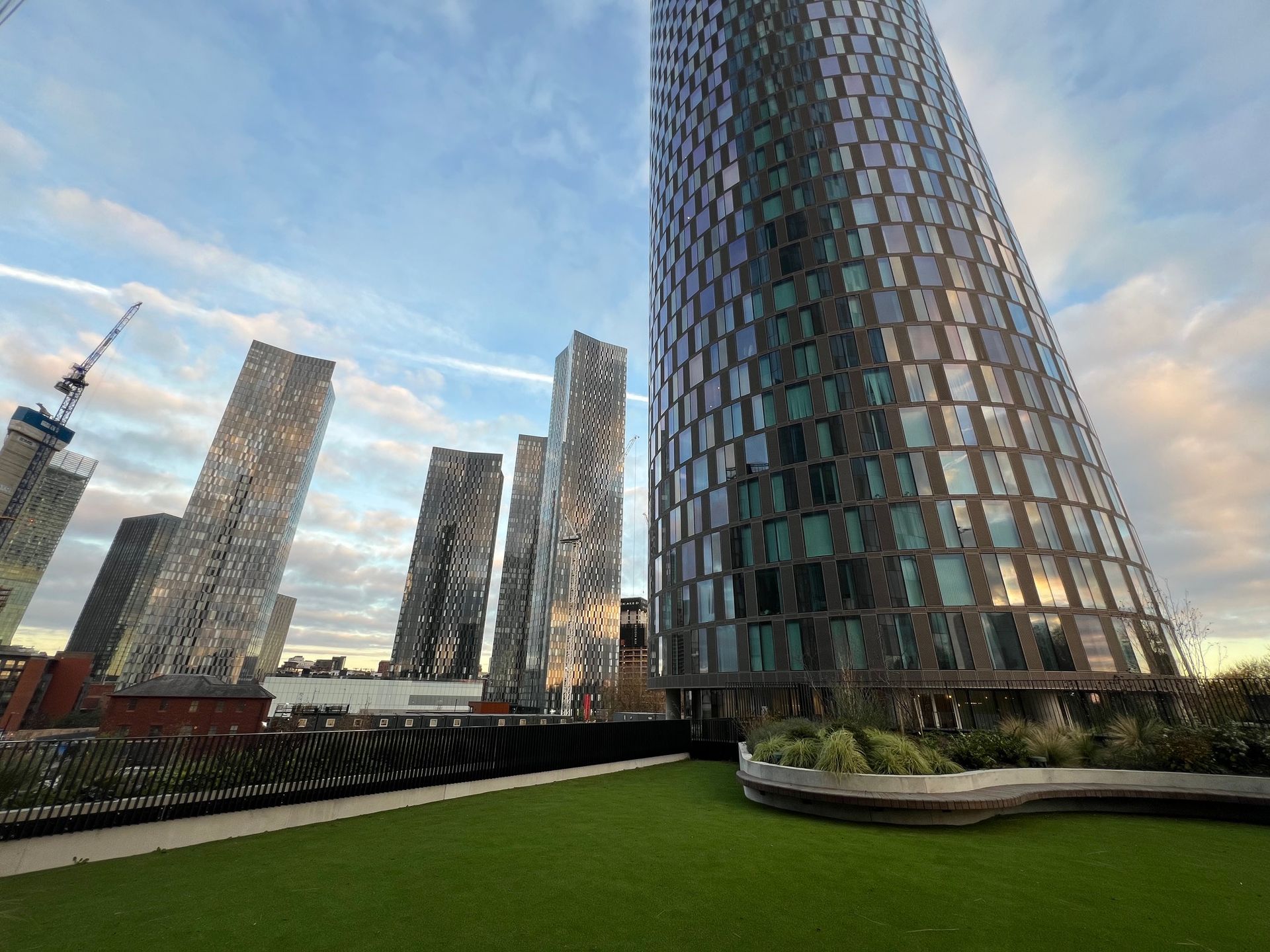 Skyscrapers against a cloudy sky, with green rooftop garden in foreground.