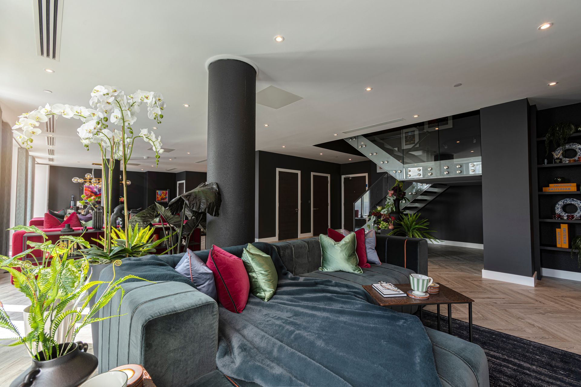Luxurious living room with a chaise lounge, dark walls, and stairs in background.
