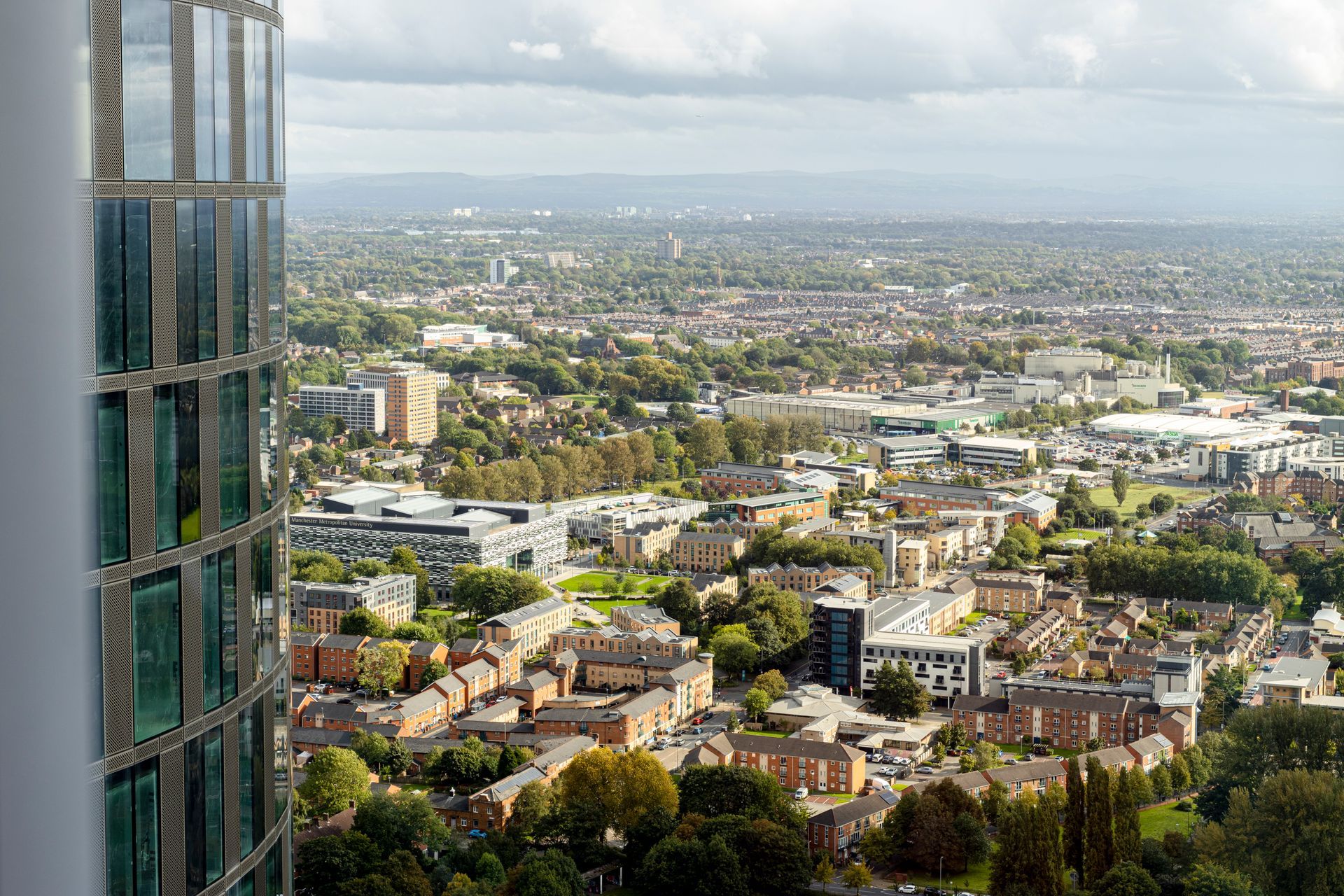 View of a city from a high-rise building with a patterned glass exterior, overcast sky.