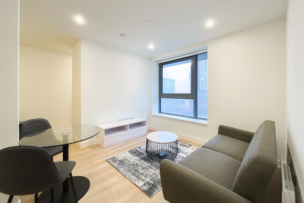 Modern living room with sofa, coffee table, rug, dining table, and large window.