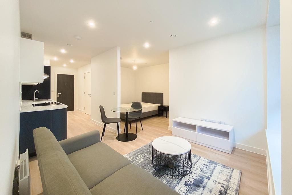 Modern studio apartment interior with kitchen, bed, seating area, and coffee table.