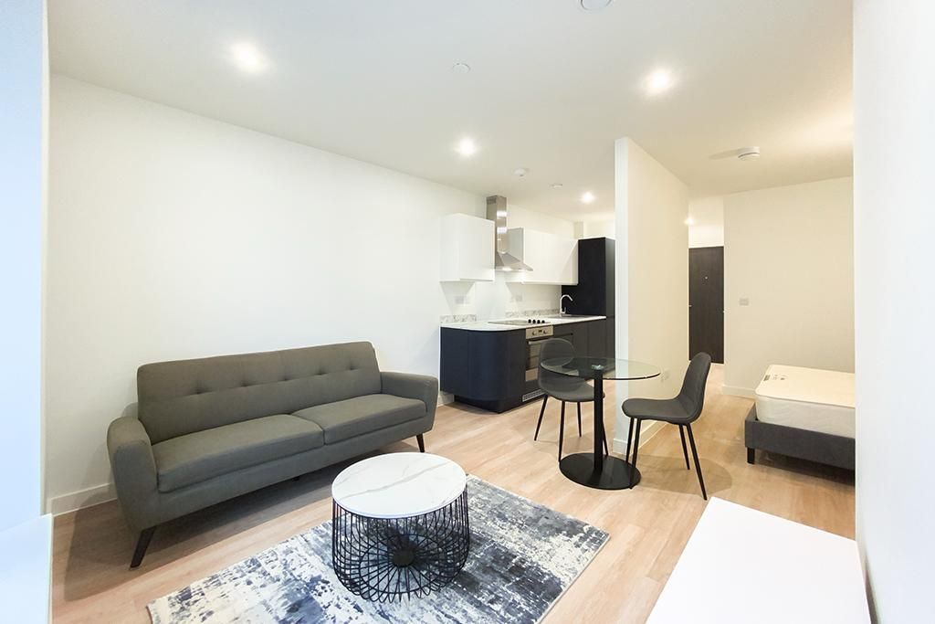 Modern apartment interior with sofa, coffee table, and open kitchen.