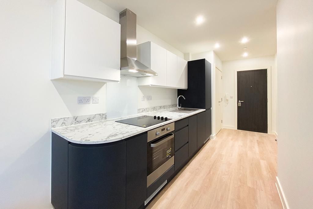 Modern kitchen with white and black cabinets, stainless steel appliances, and wood-look flooring.