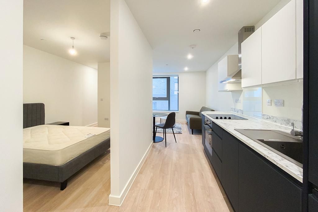 Modern apartment interior with kitchen, dining area, and bedroom visible.
