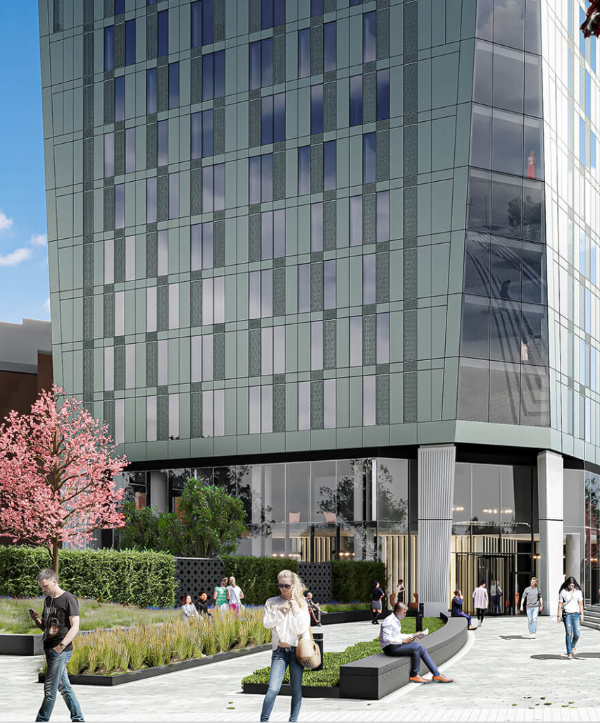 Modern high-rise building with glass facade, people walking, seating area, and pink flowering tree.