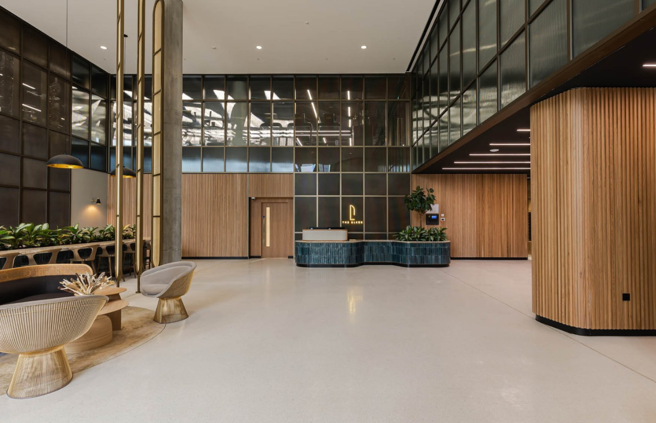 Modern lobby with light wood paneling, a reception desk, and large windows.