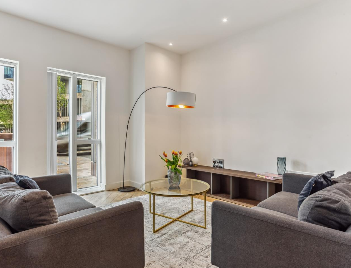 Living room with gray sofas, glass coffee table, and an arched floor lamp.