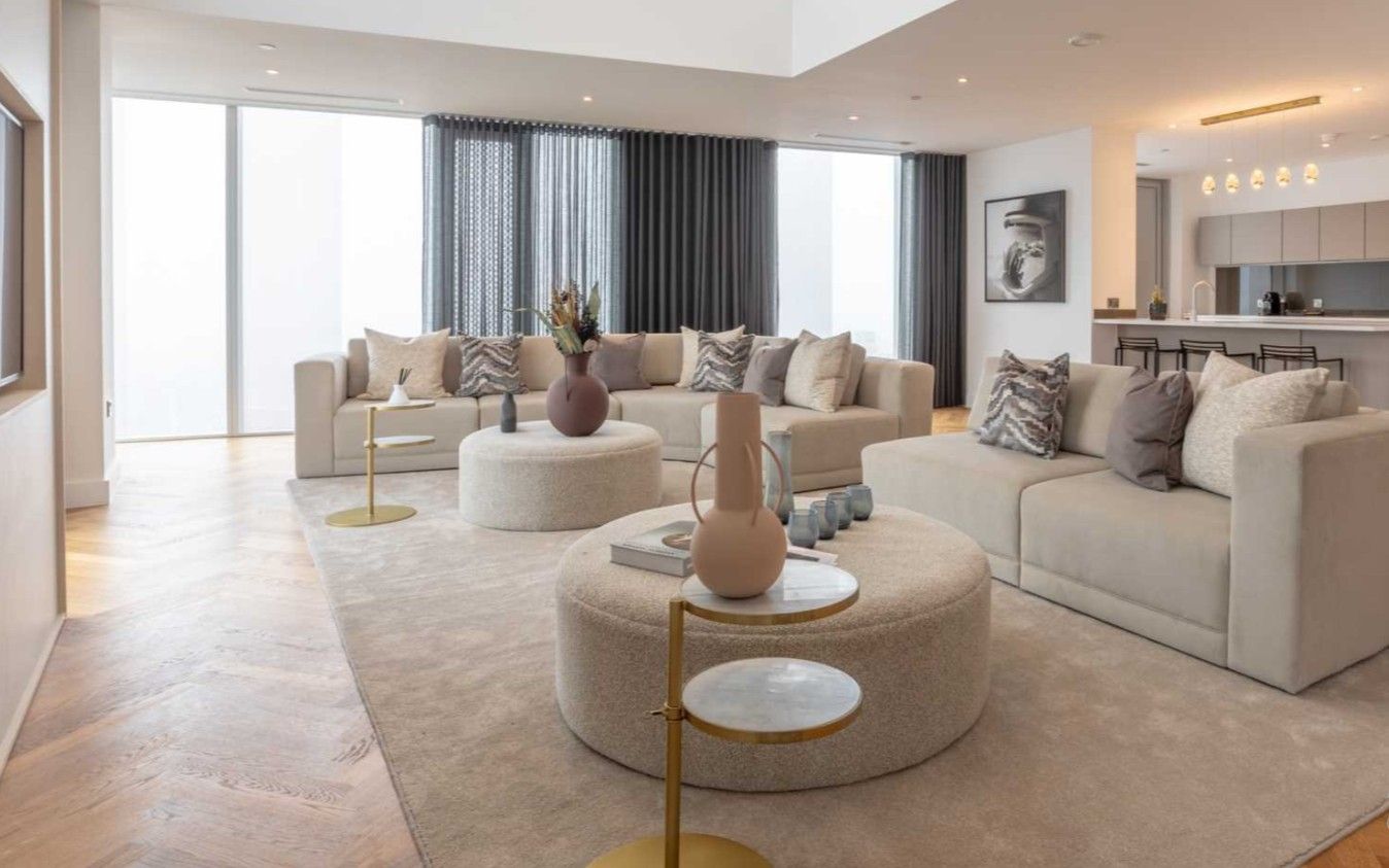 Spacious living room with light-colored furniture, large windows, and a neutral color palette.