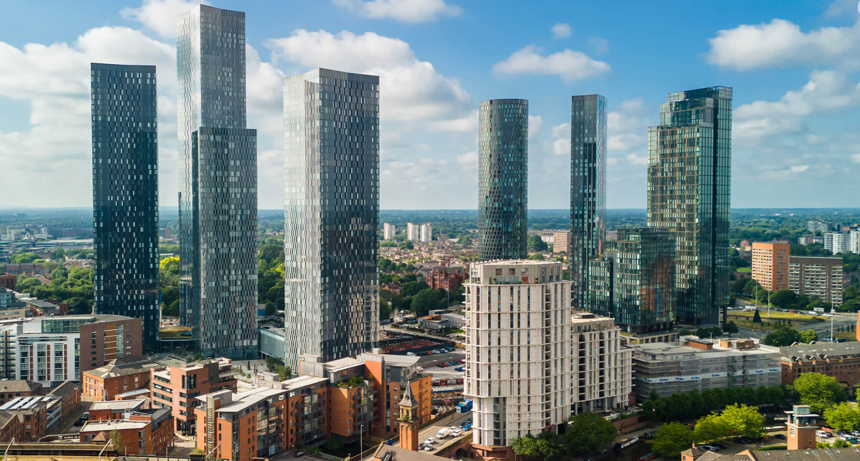 High-rise city buildings against a blue sky with scattered clouds.