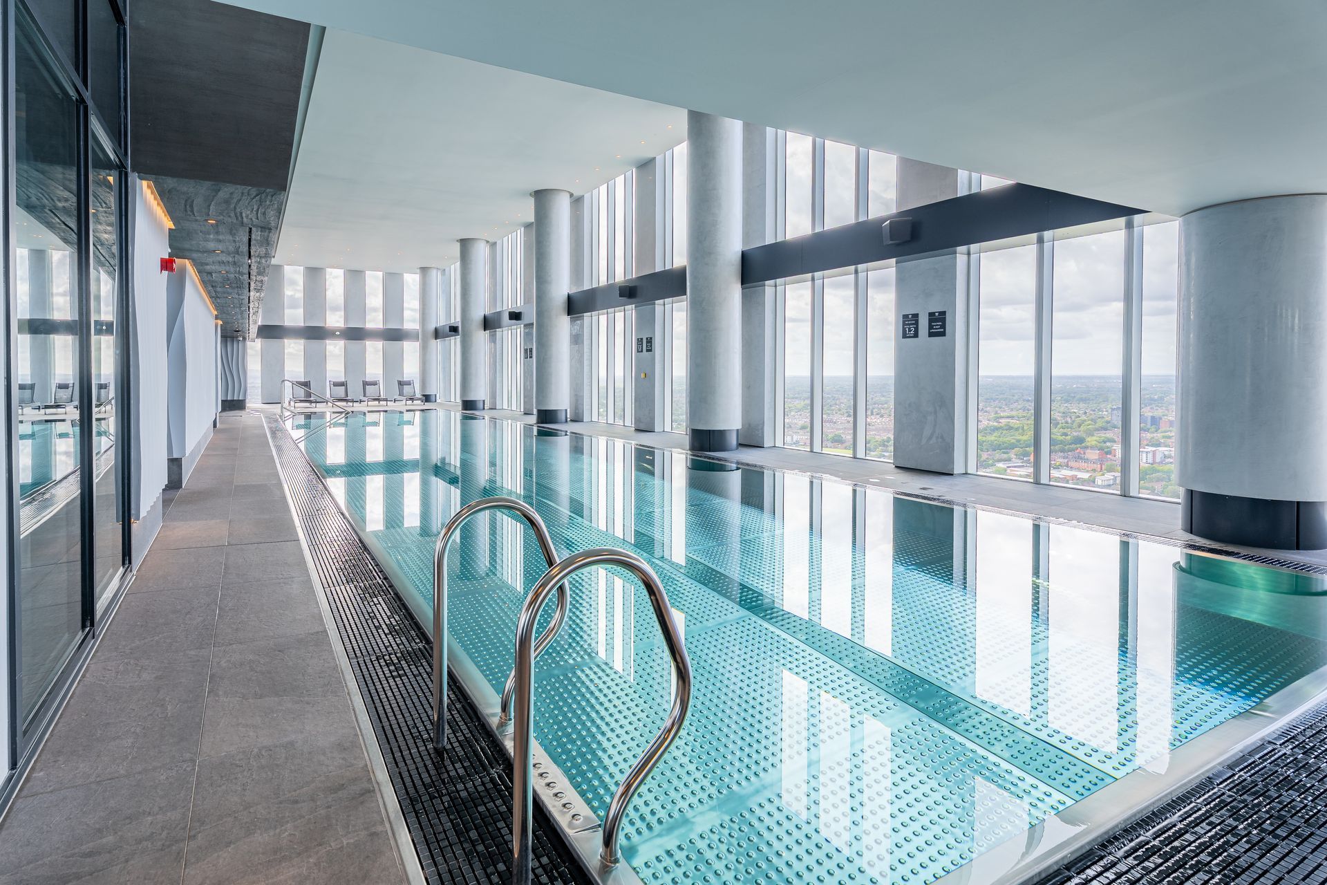 An indoor lap pool with floor-to-ceiling windows and city views.