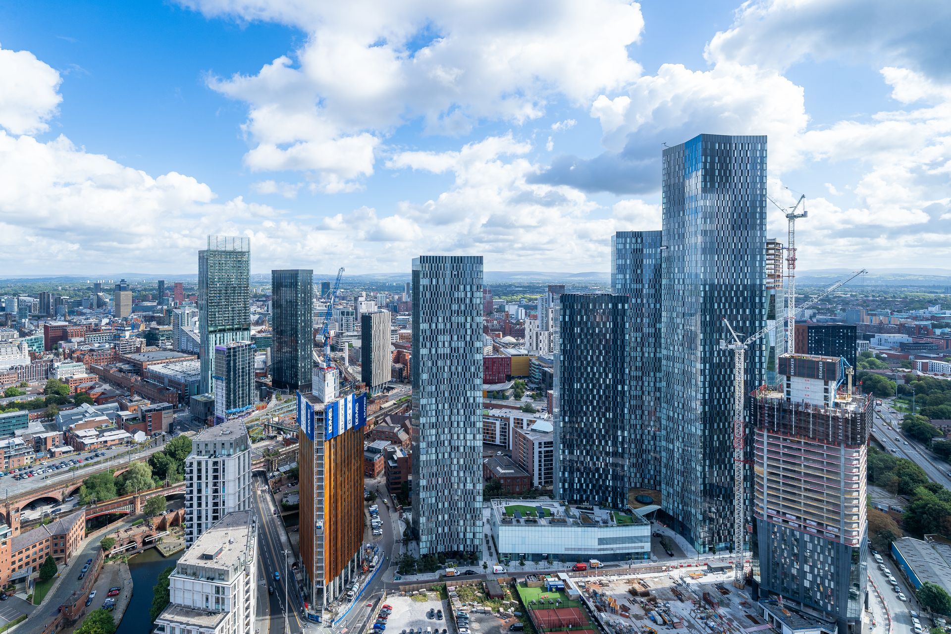 City skyline with tall modern skyscrapers under a partly cloudy sky.