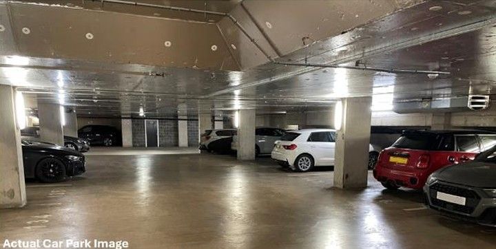 Cars parked in a multi-level indoor parking garage with concrete columns and ceiling, and a polished floor.