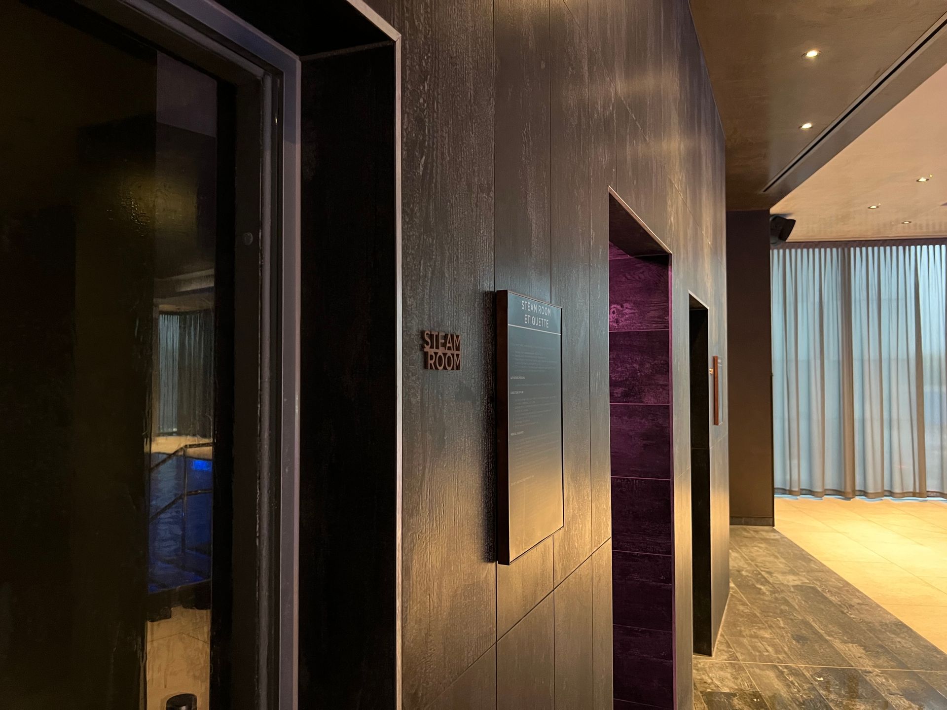 Elevator bank with textured dark wood paneling, purple tile inside the elevator doors.