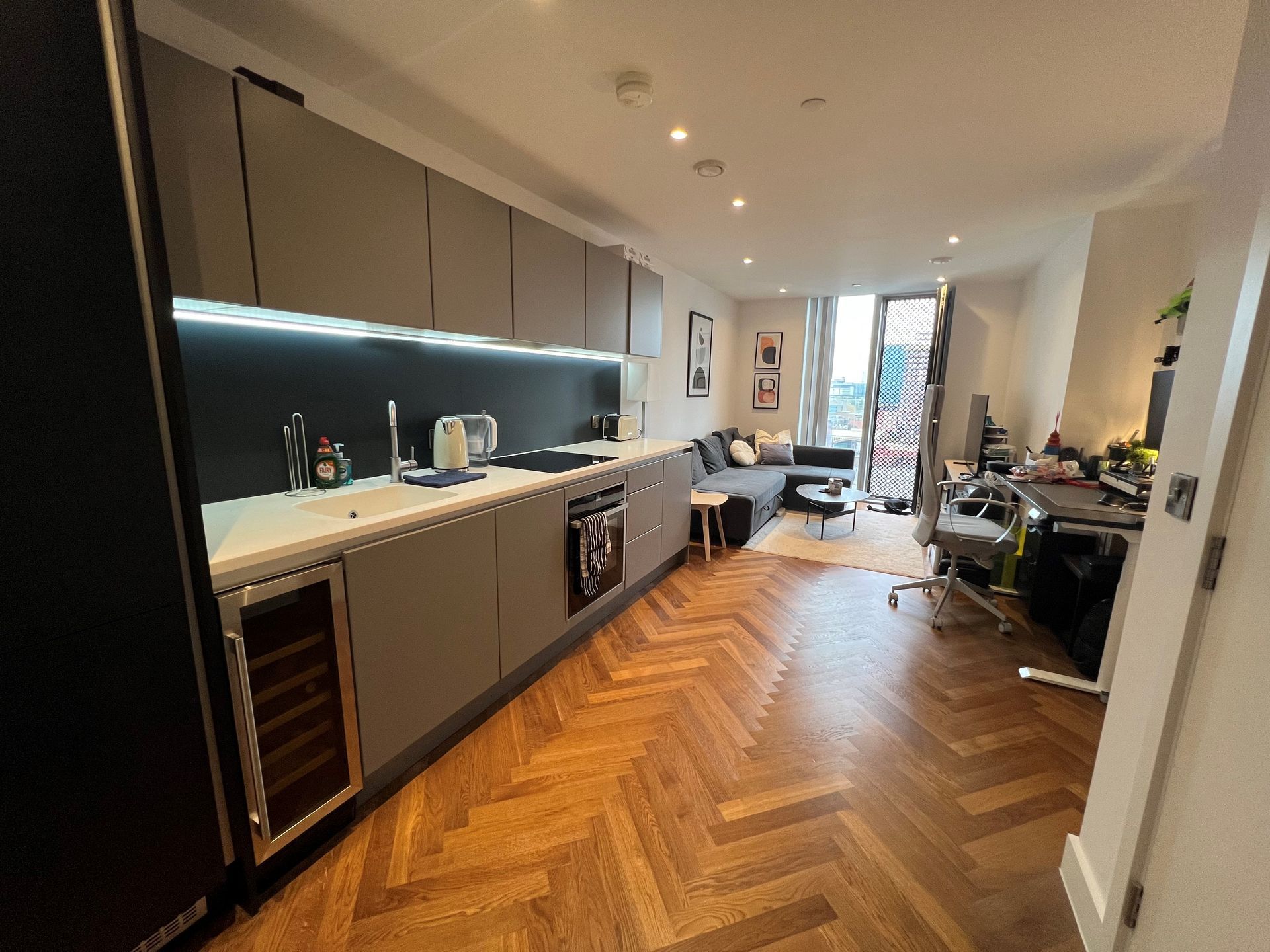 Modern apartment interior with kitchen, living area, and wood floors.
