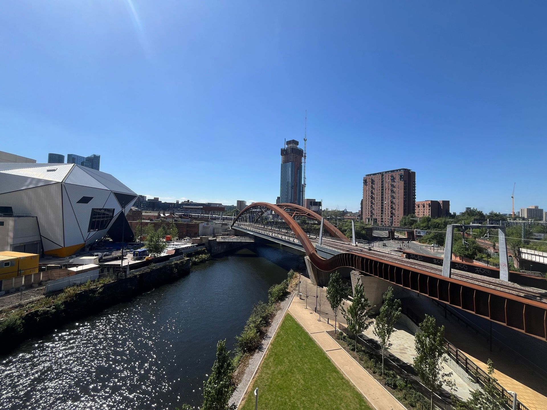 River with bridges under a clear blue sky. Buildings and a tall tower in the background.