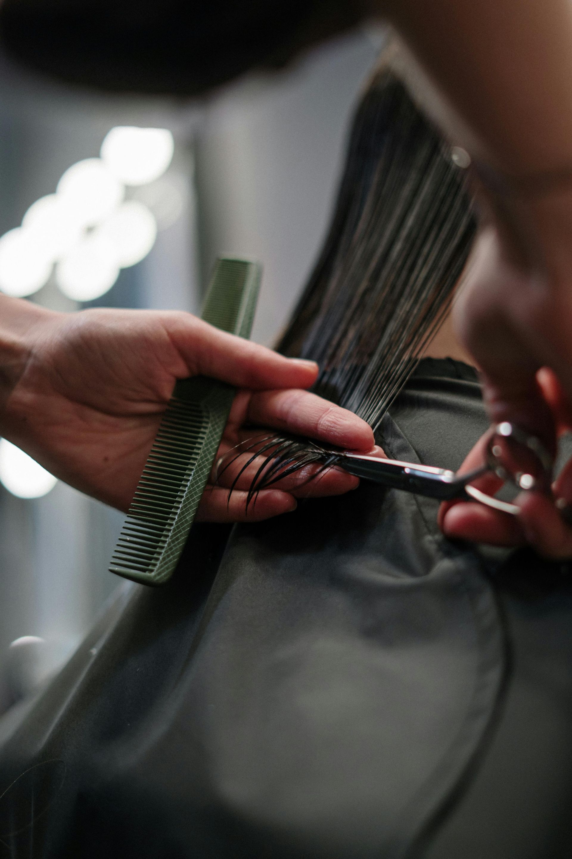 Hairdresser cutting hair with comb and scissors in a salon.