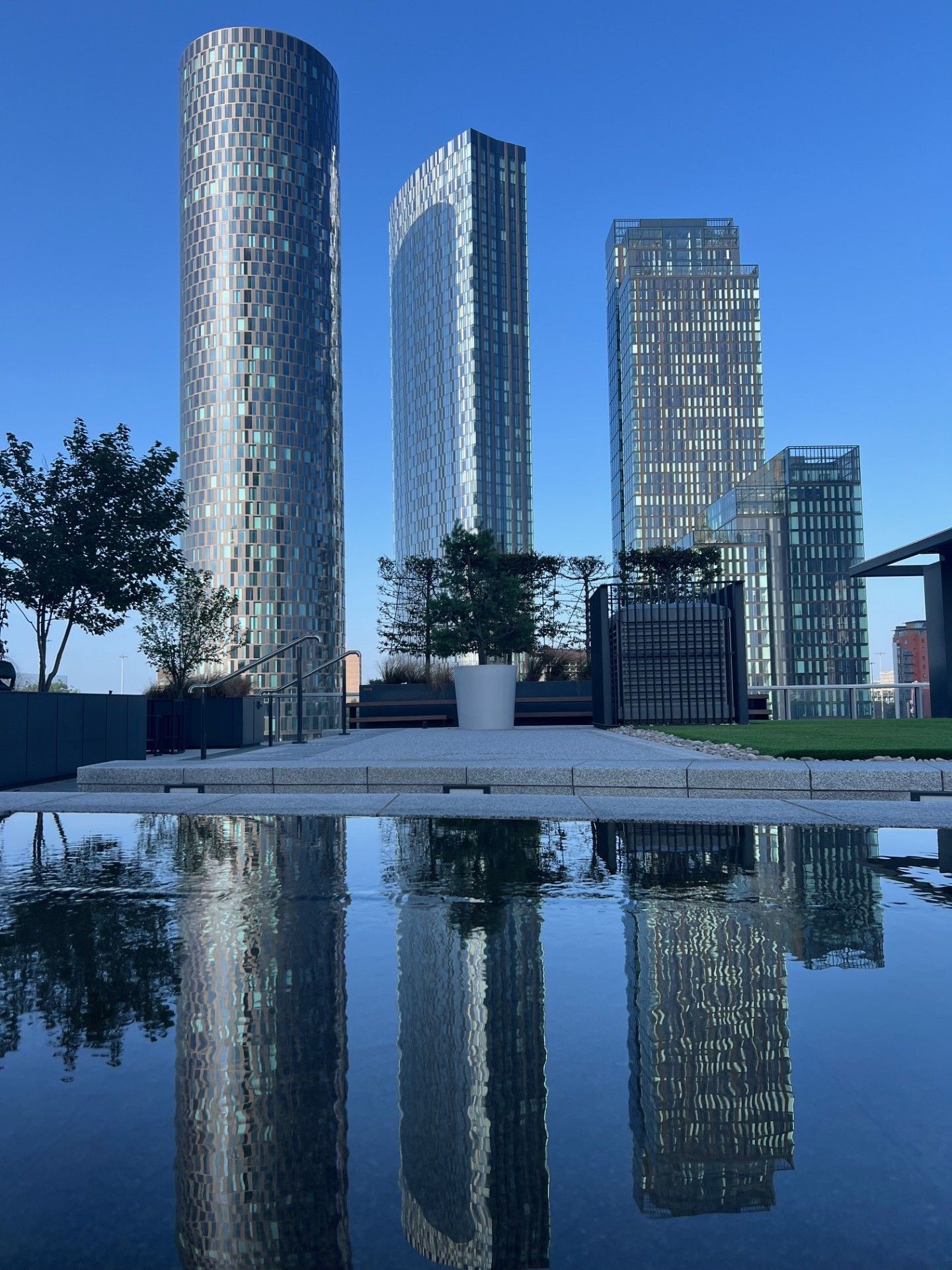 Skyscrapers reflected in water on a sunny day.