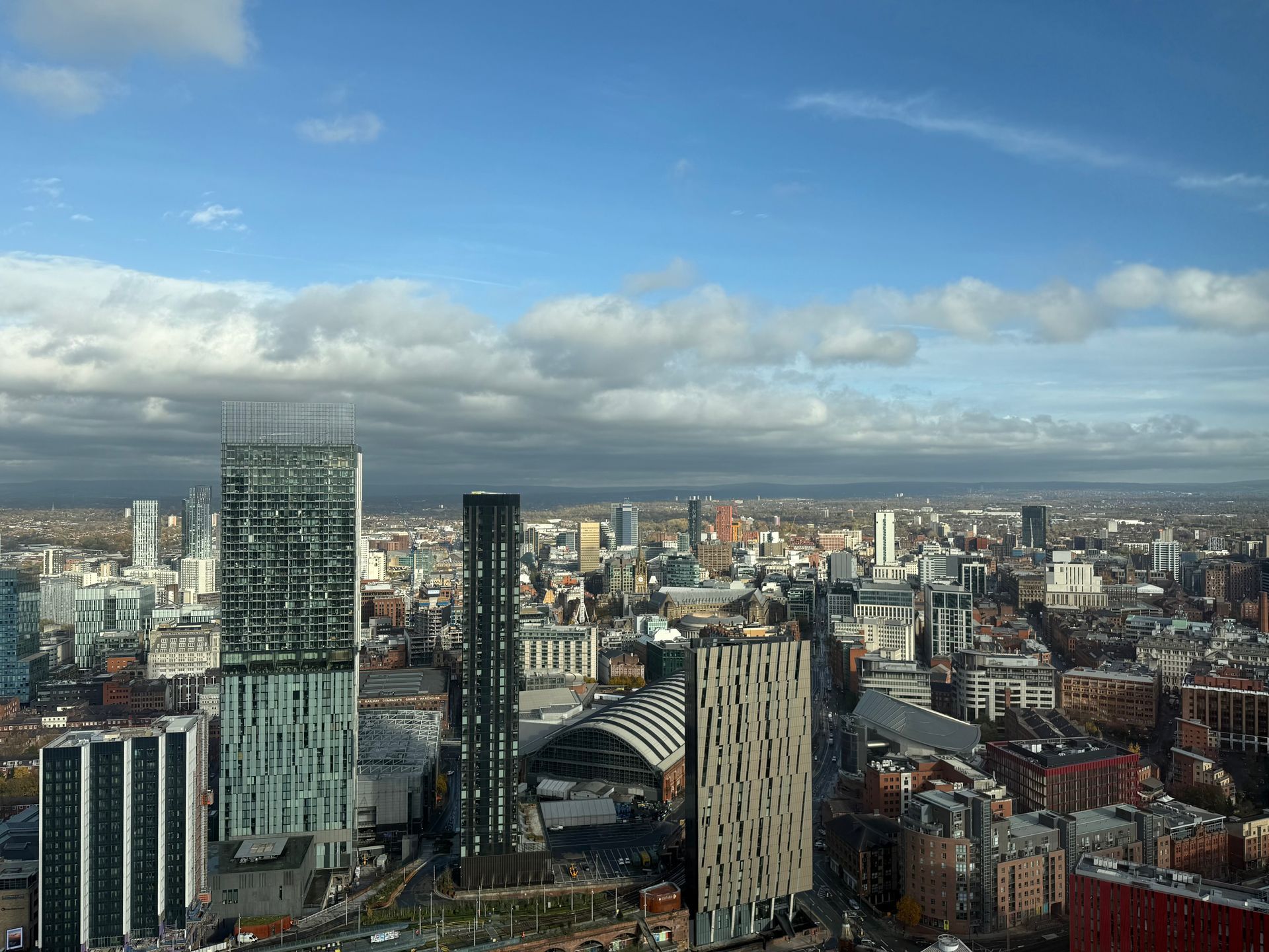 Cityscape under a partly cloudy sky, featuring tall modern buildings.