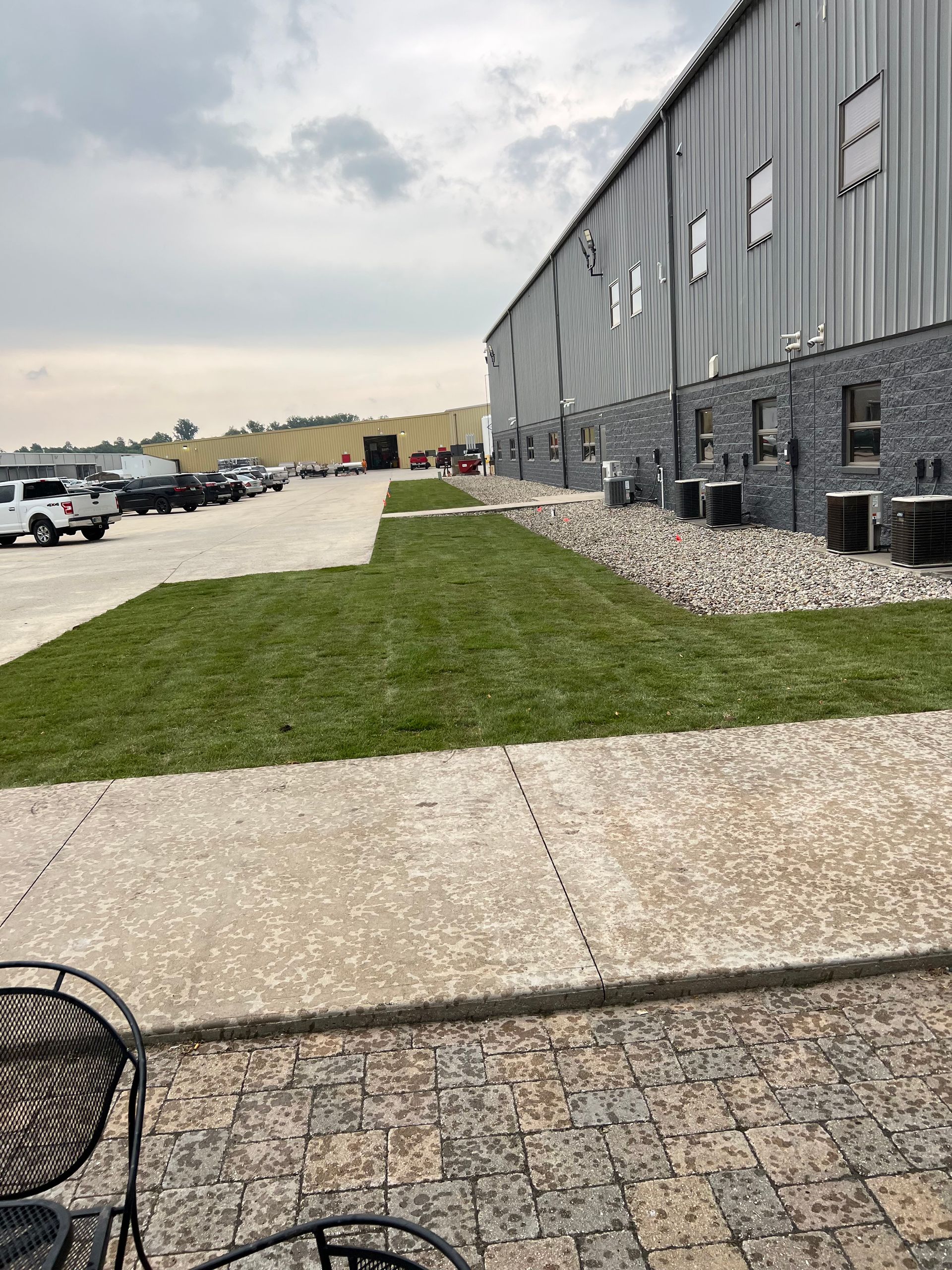 Exterior of a gray building with grass, landscaping, and a parking lot on an overcast day.