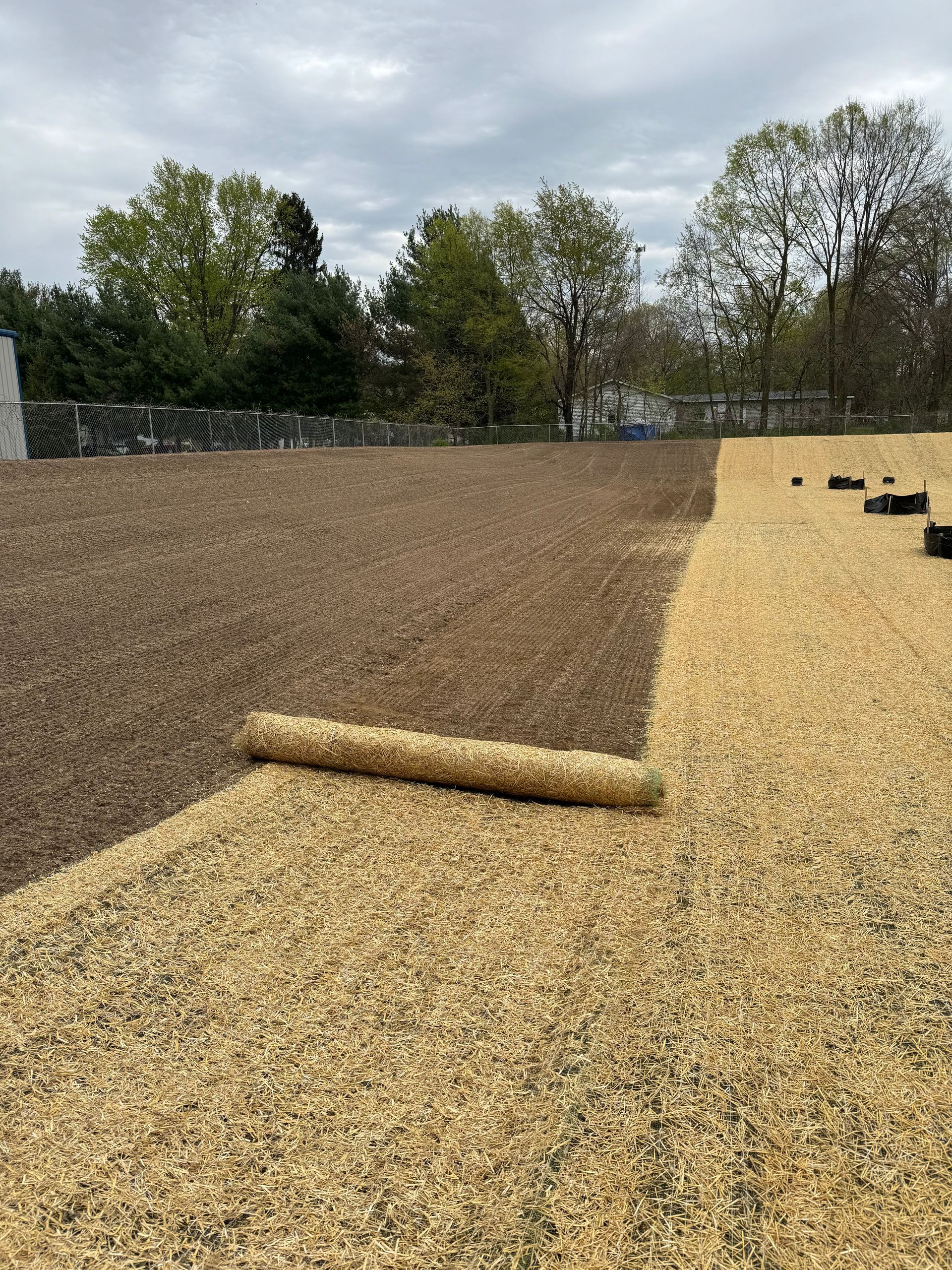 Wood chip playground area, with dark brown and tan sections separated by a roll of material.