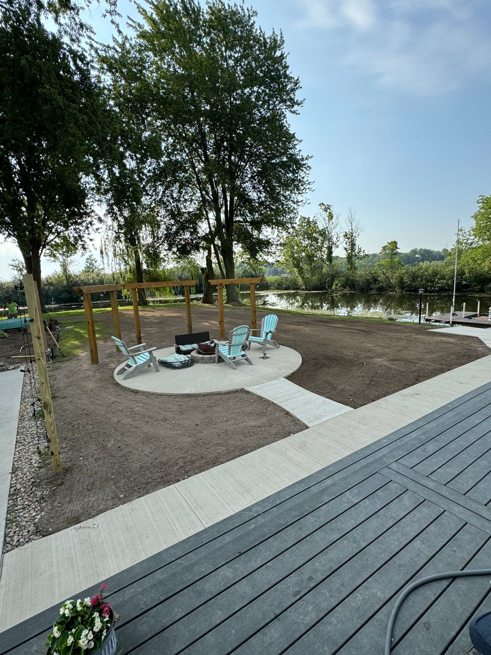 Outdoor seating area with chairs around a fire pit, near a water body.