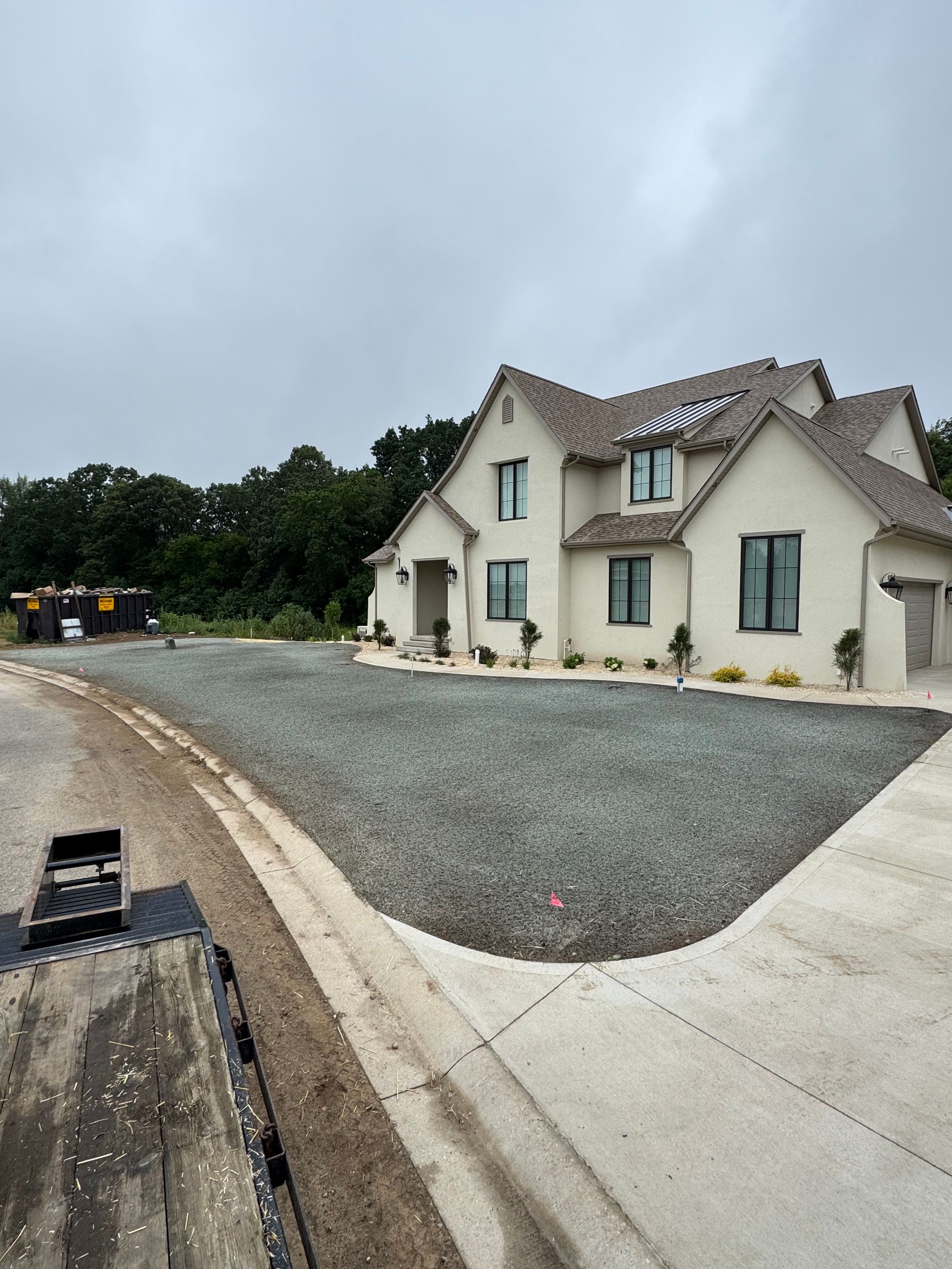 House under construction with gravel yard, cloudy sky.