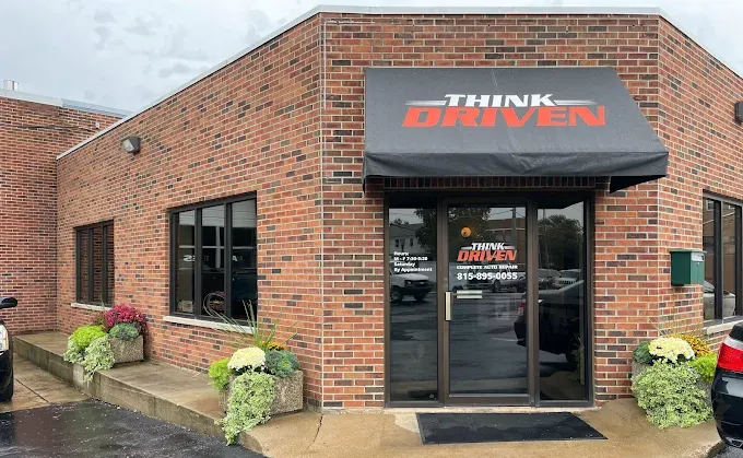 Brick building with Think Driven sign above glass entrance, featuring a black awning and planters.