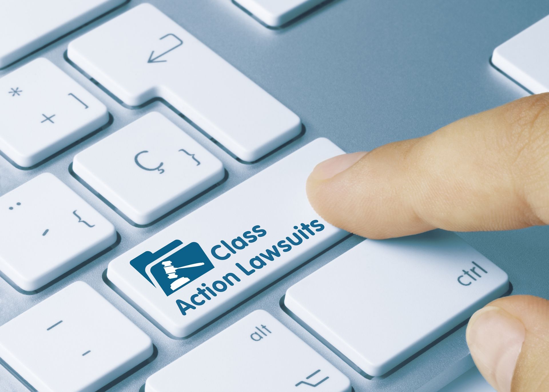 A person pressing a key on a keyboard that says class action lawsuits
