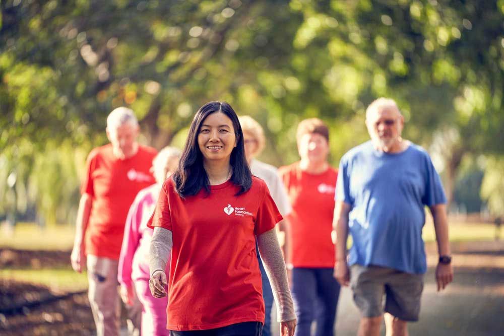 A group of people walking together outdoors on a path, with a person in the foreground leading the way.