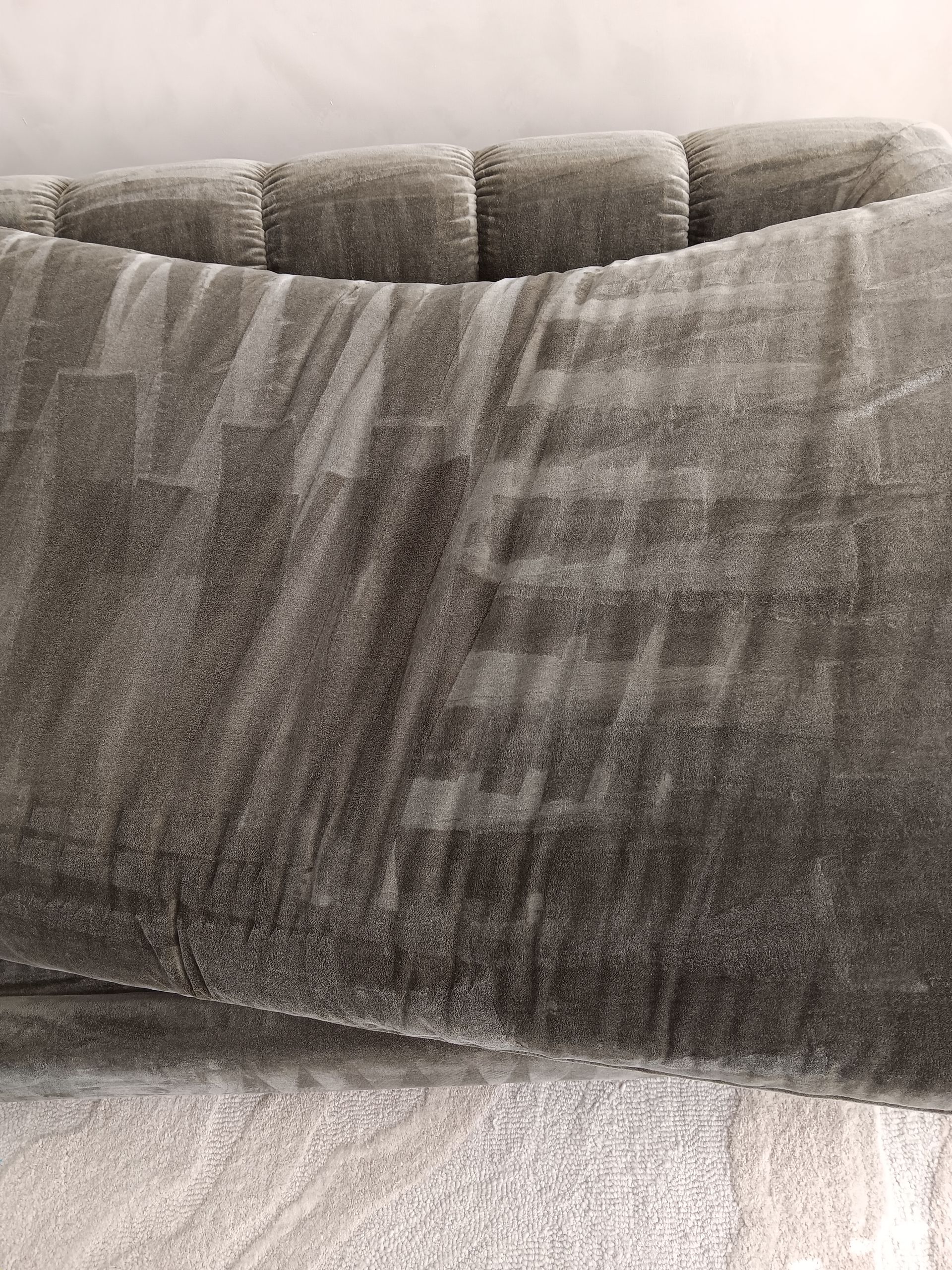 Person using carpet cleaning machine on a gray rug, cleaning a stripe.