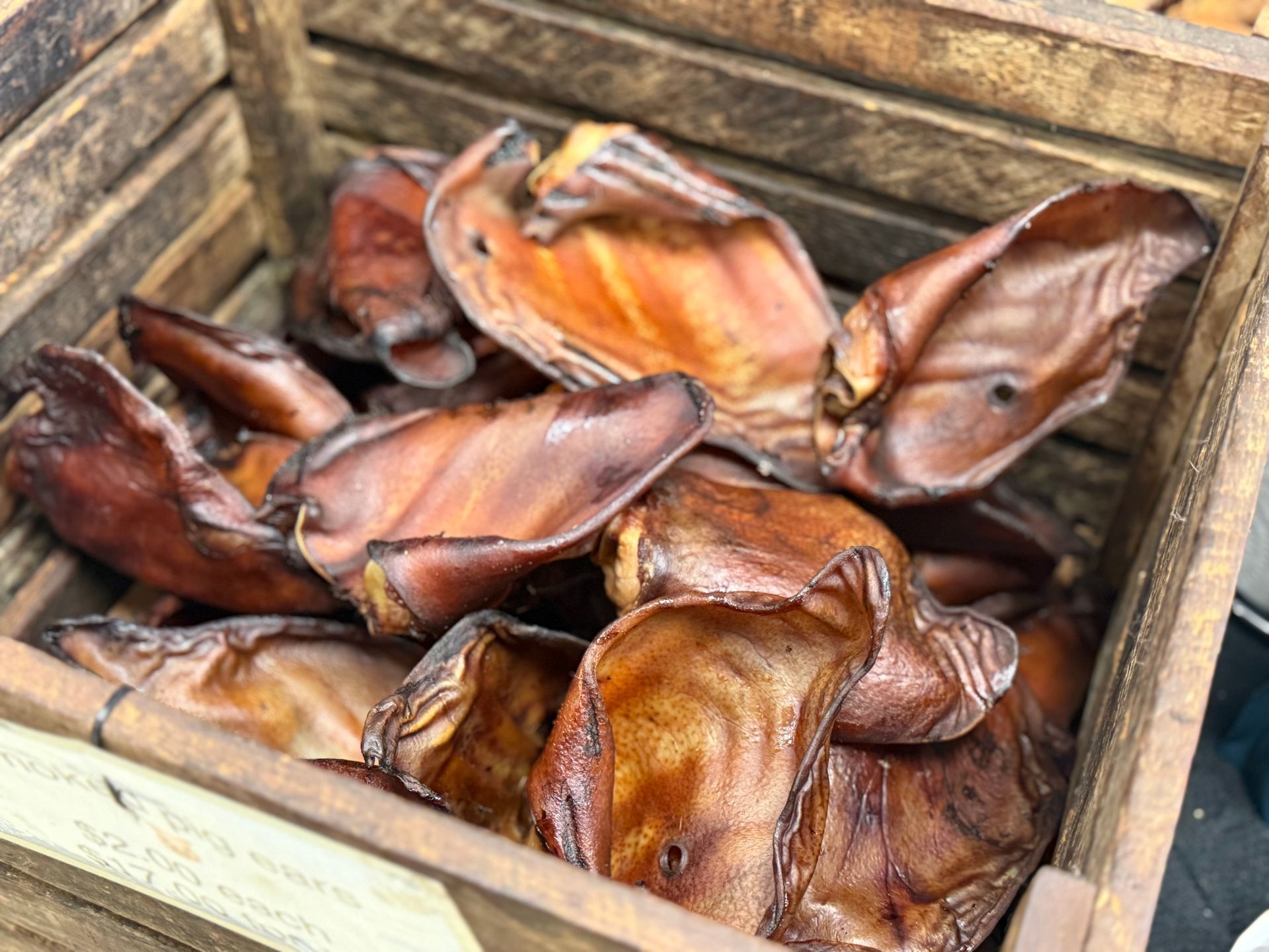 Wooden crate filled with sliced dried fruit, likely mango, in warm orange-brown tones
