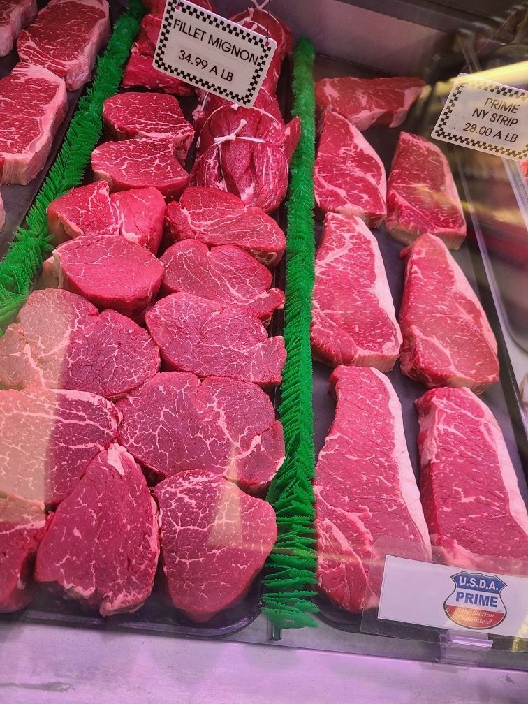 Display of raw red beef cuts in a butcher case with price labels and green dividers