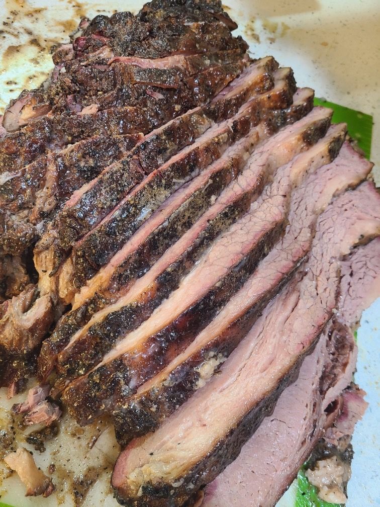 Sliced roasted beef with a dark crust on a serving plate
