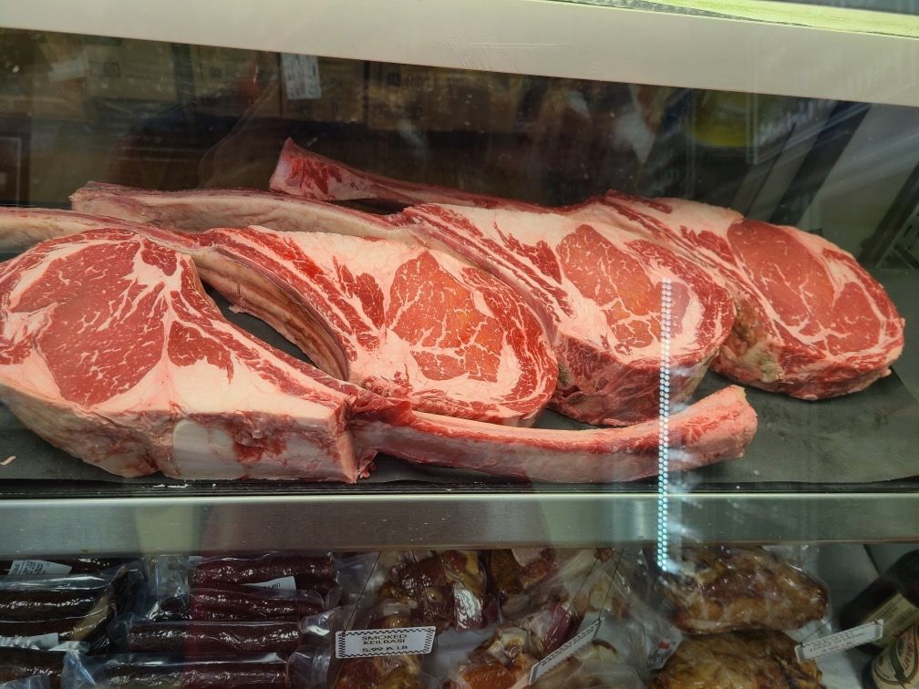 Raw marbled beef steaks displayed in a refrigerated deli case