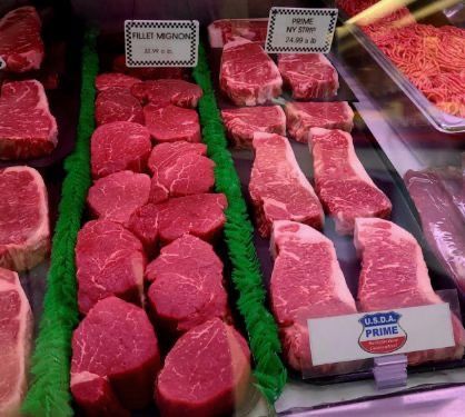 Fresh red cuts of beef displayed in a butcher shop meat case with price labels