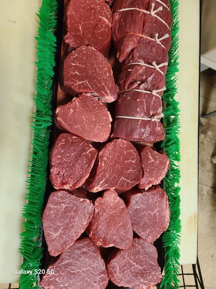 Tray of raw beef cuts arranged in rows on a green-lined display.