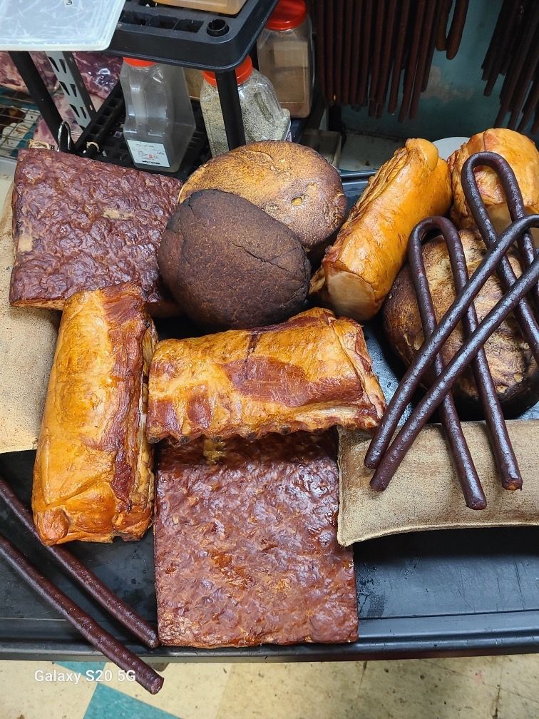 Assorted baked pastries and bread on a tray, including rolls, buns, and square cakes, in brown and golden tones