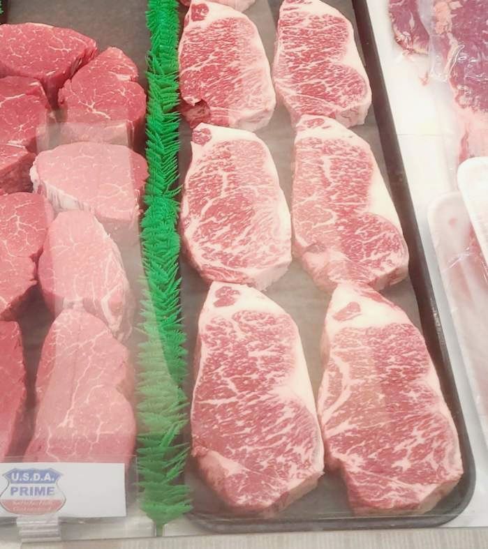 Tray of raw marbled beef steaks displayed in a grocery meat case
