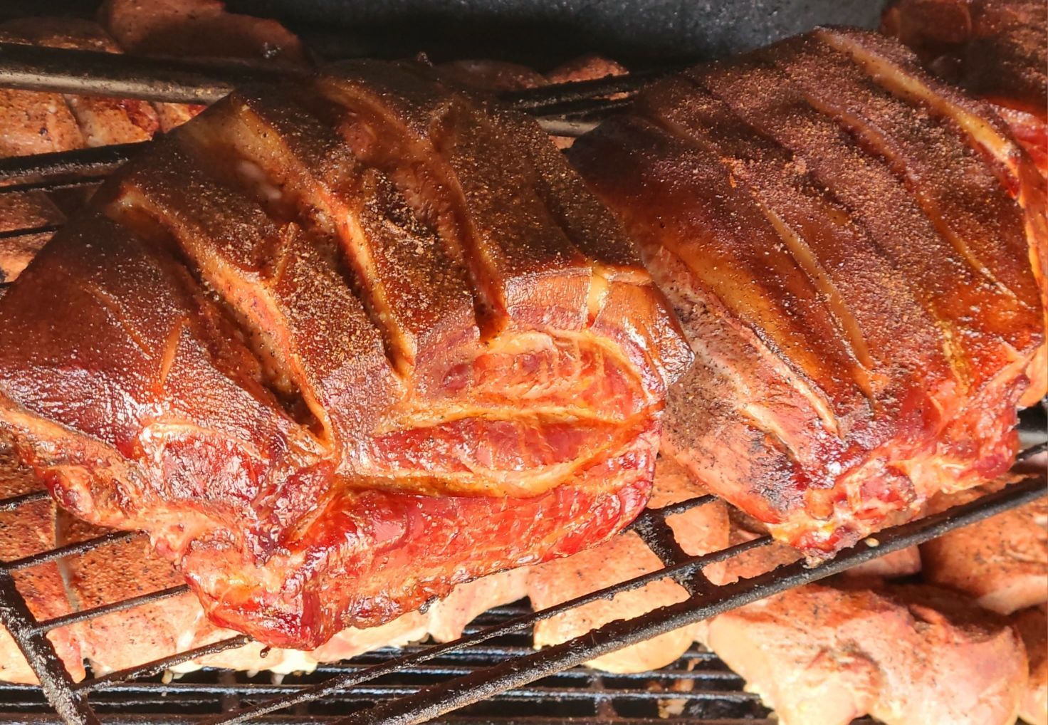 Barbecue ribs with sauce cooking on a grill, browned and glossy under the heat