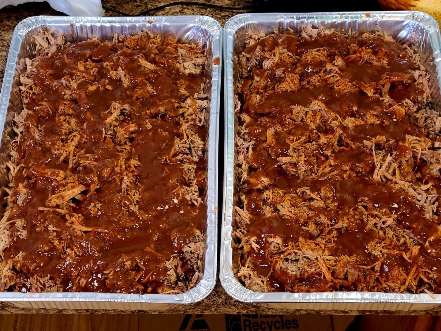 Two aluminum trays filled with baked casserole topped with melted cheese and browned sauce