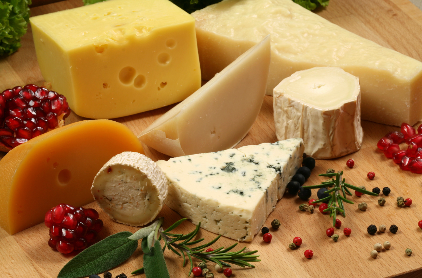 Assorted cheeses with berries and herbs on a wooden board