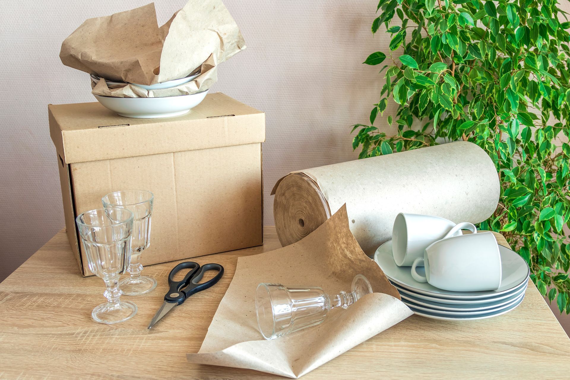 Using eco-friendly brown paper to pack dishes into moving boxes