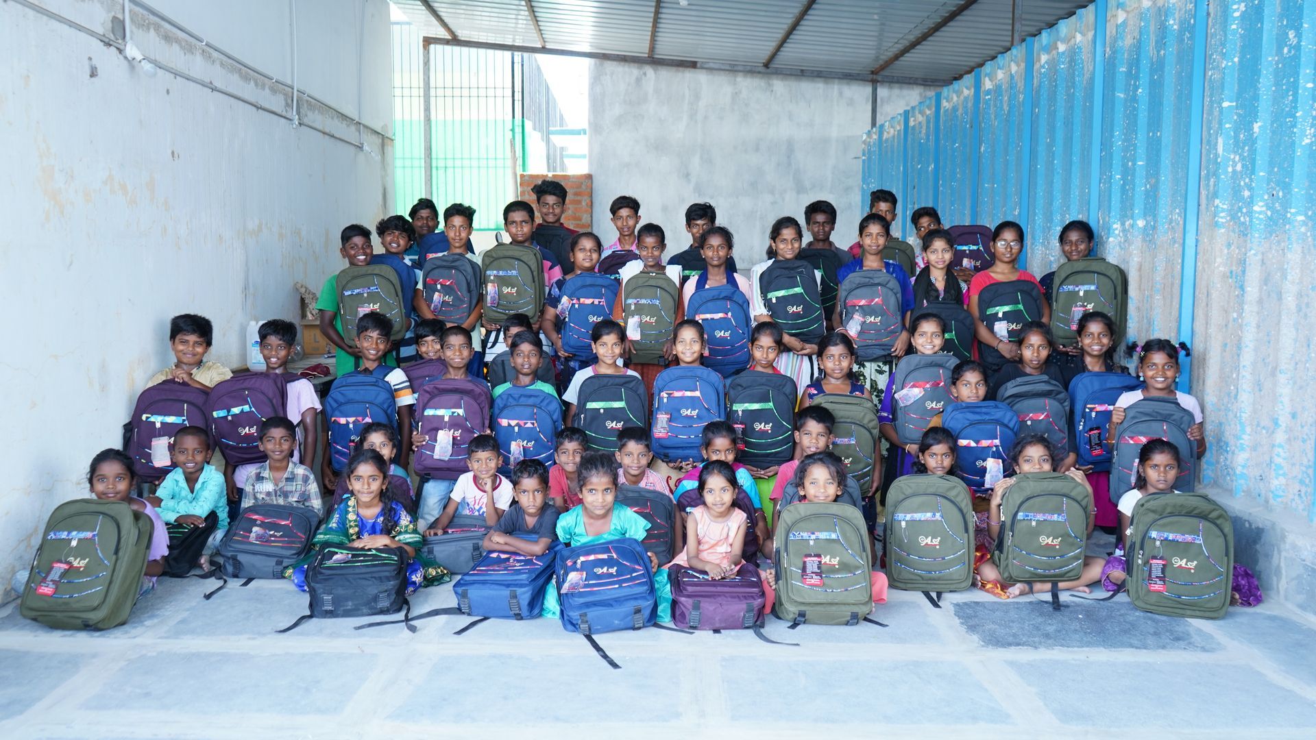 Group of children with backpacks in a room, smiling at the camera.