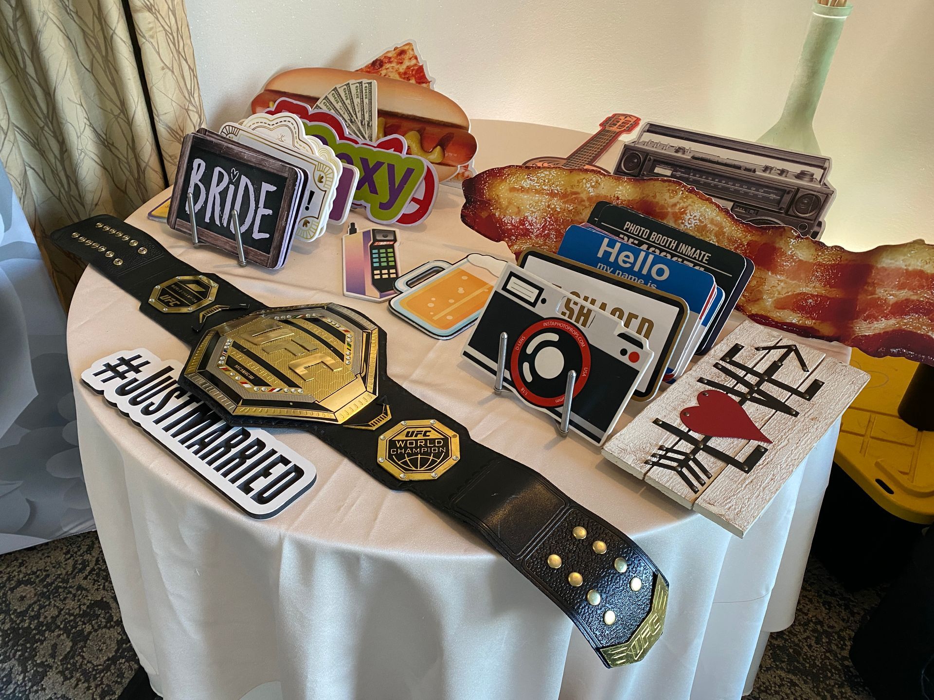 Table of premium photo booth props including signs and a championship belt