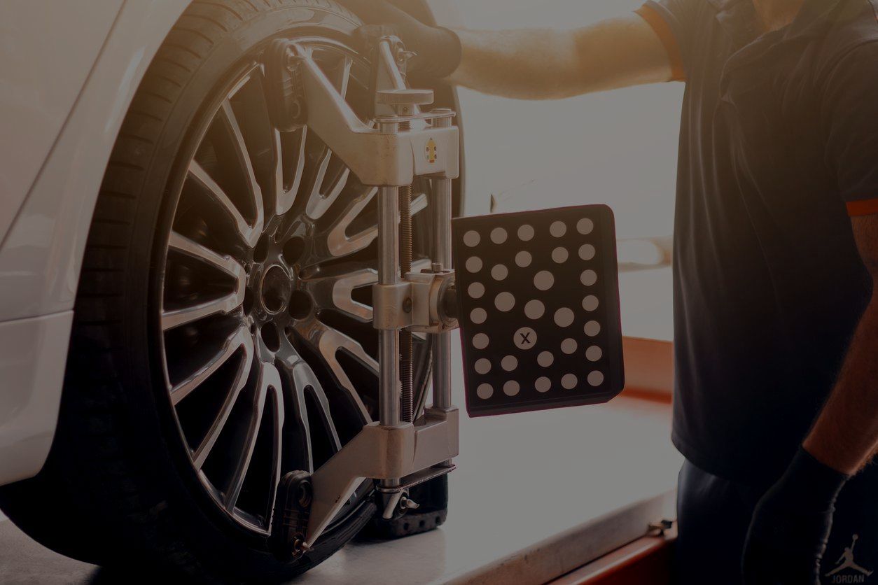 A man is working on a car on a lift in a garage.