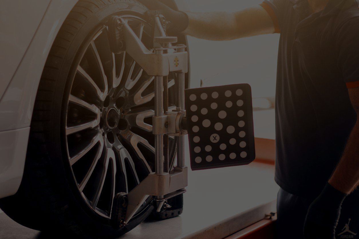 A man is working on a car on a lift in a garage.
