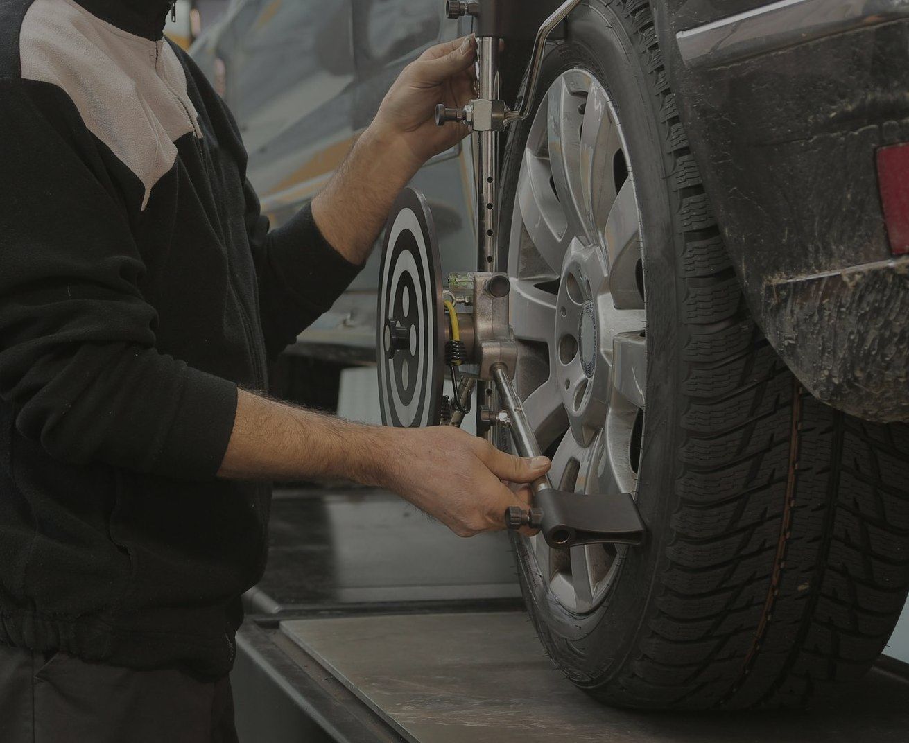 A man is adjusting a tire on a car with a machine.