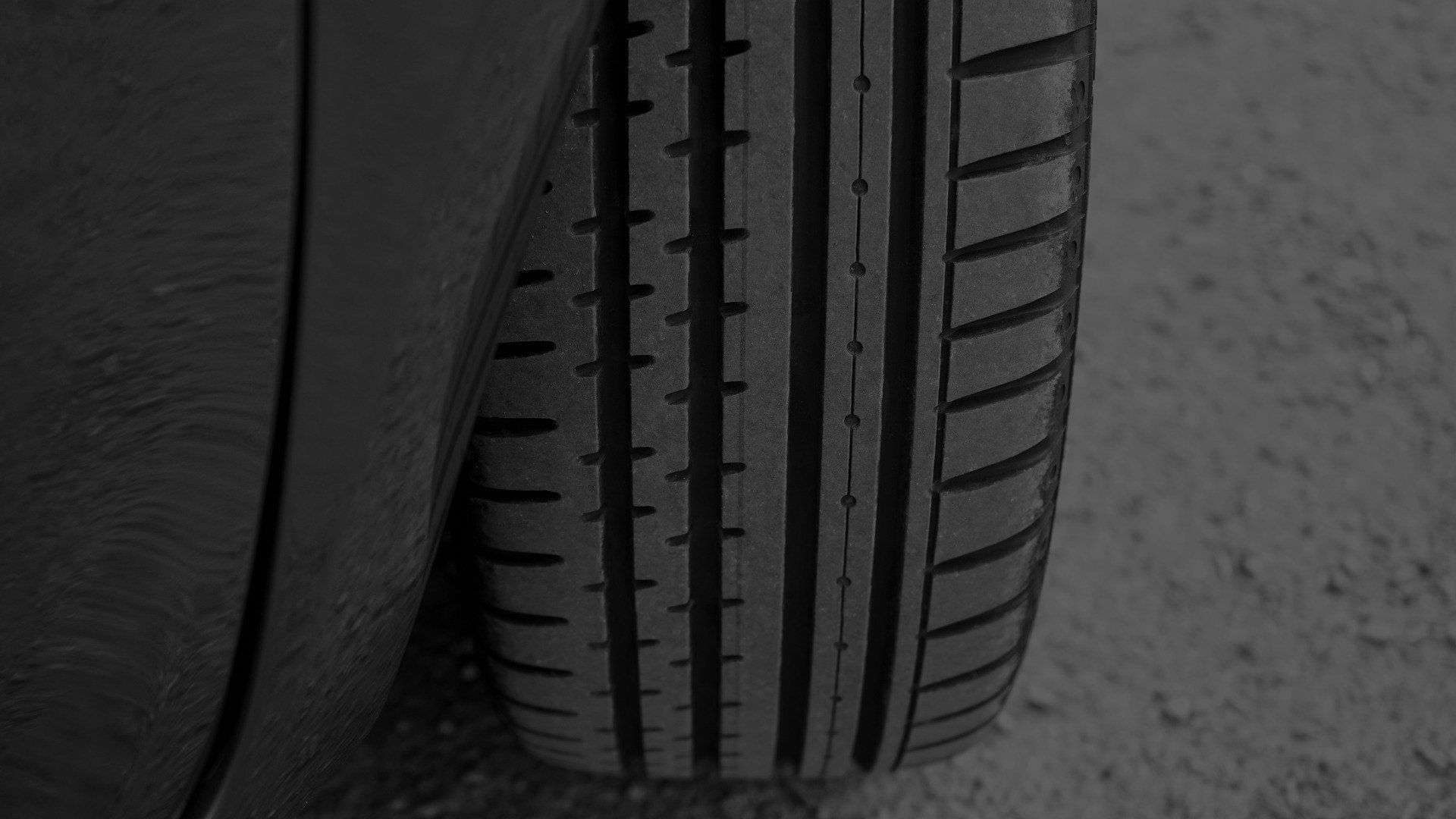 A black and white photo of a car tire on the ground.