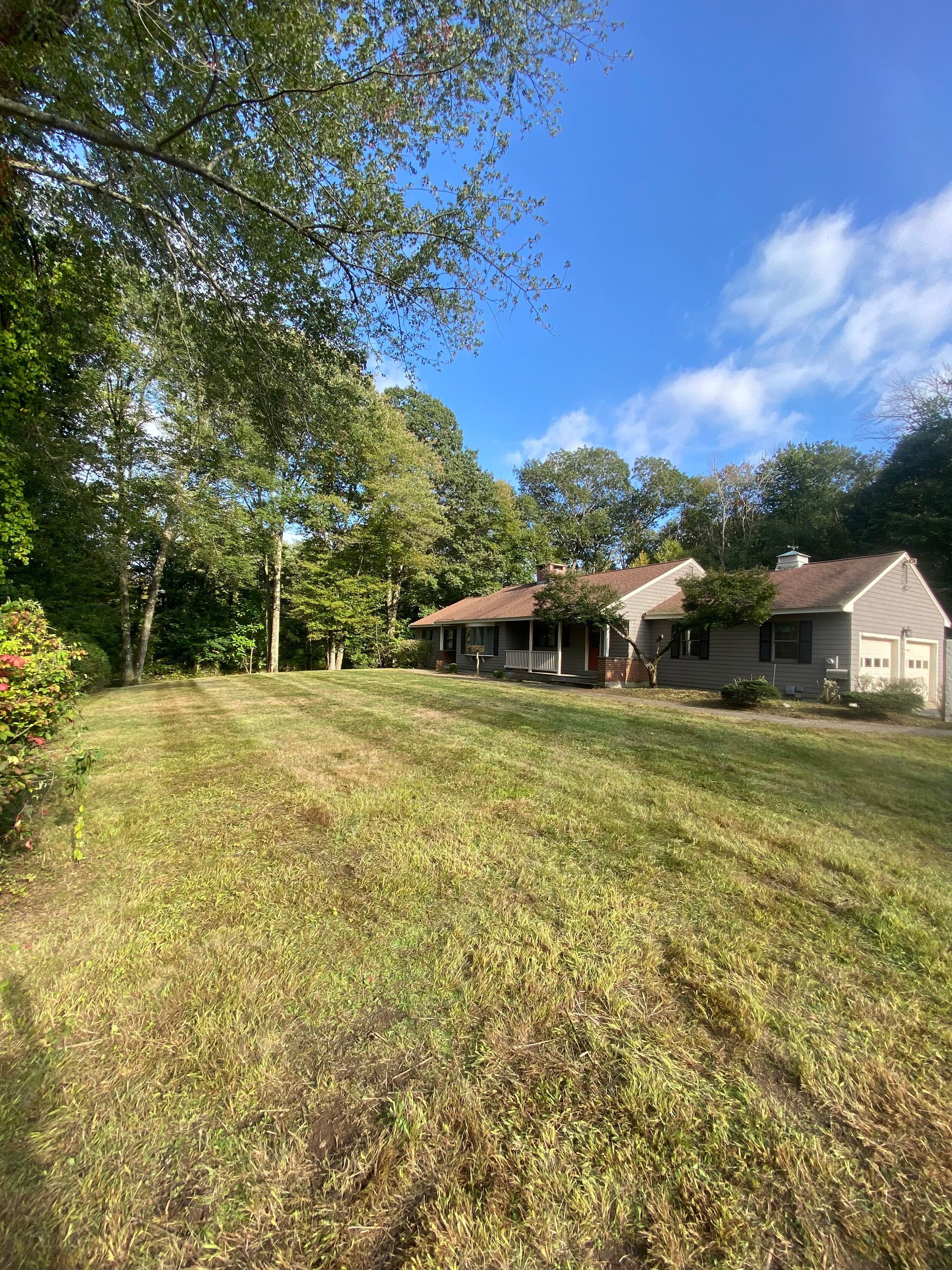A house is sitting on top of a lush green field surrounded by trees.
