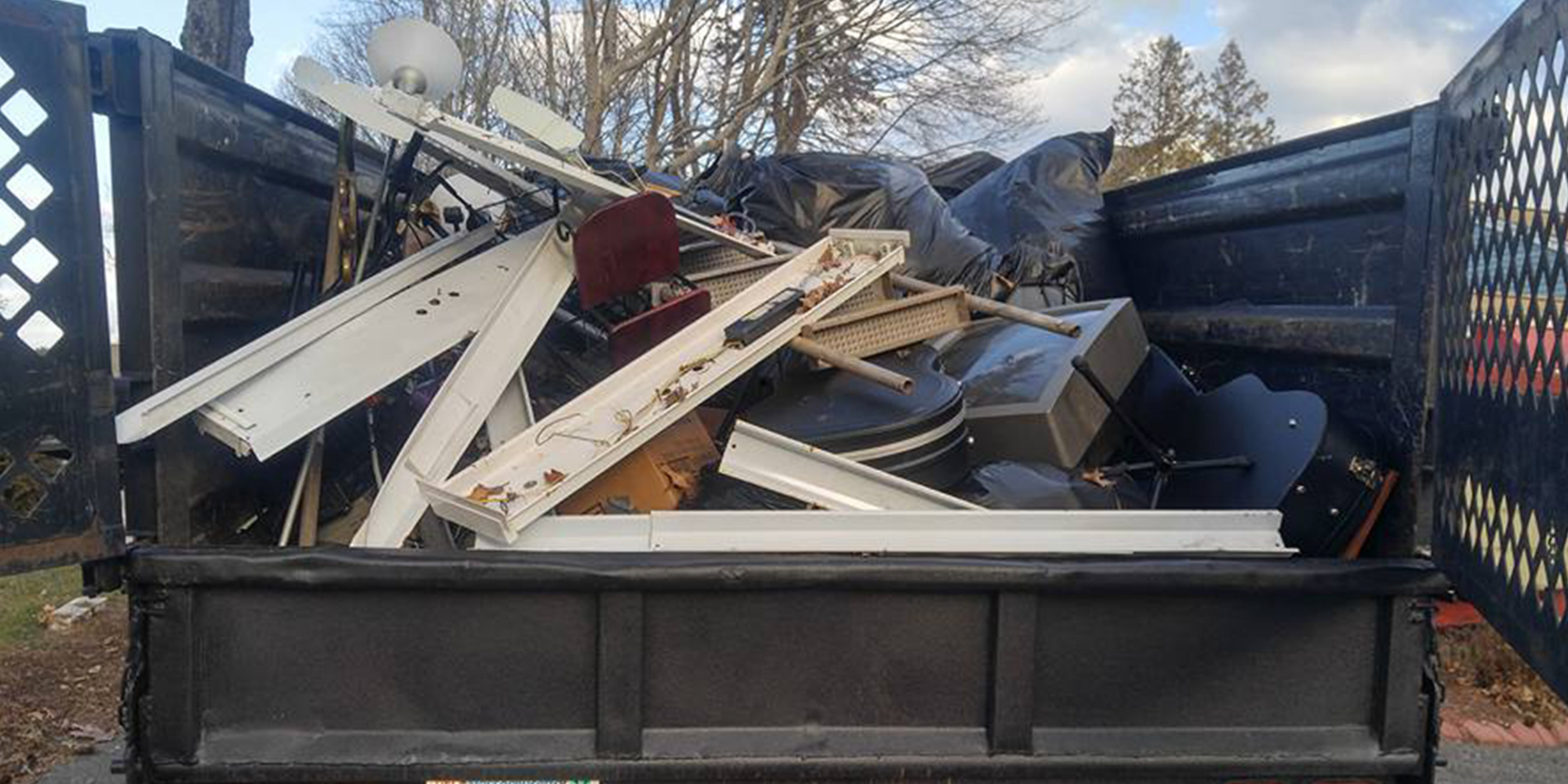 A dumpster filled with junk is sitting on the side of the road.